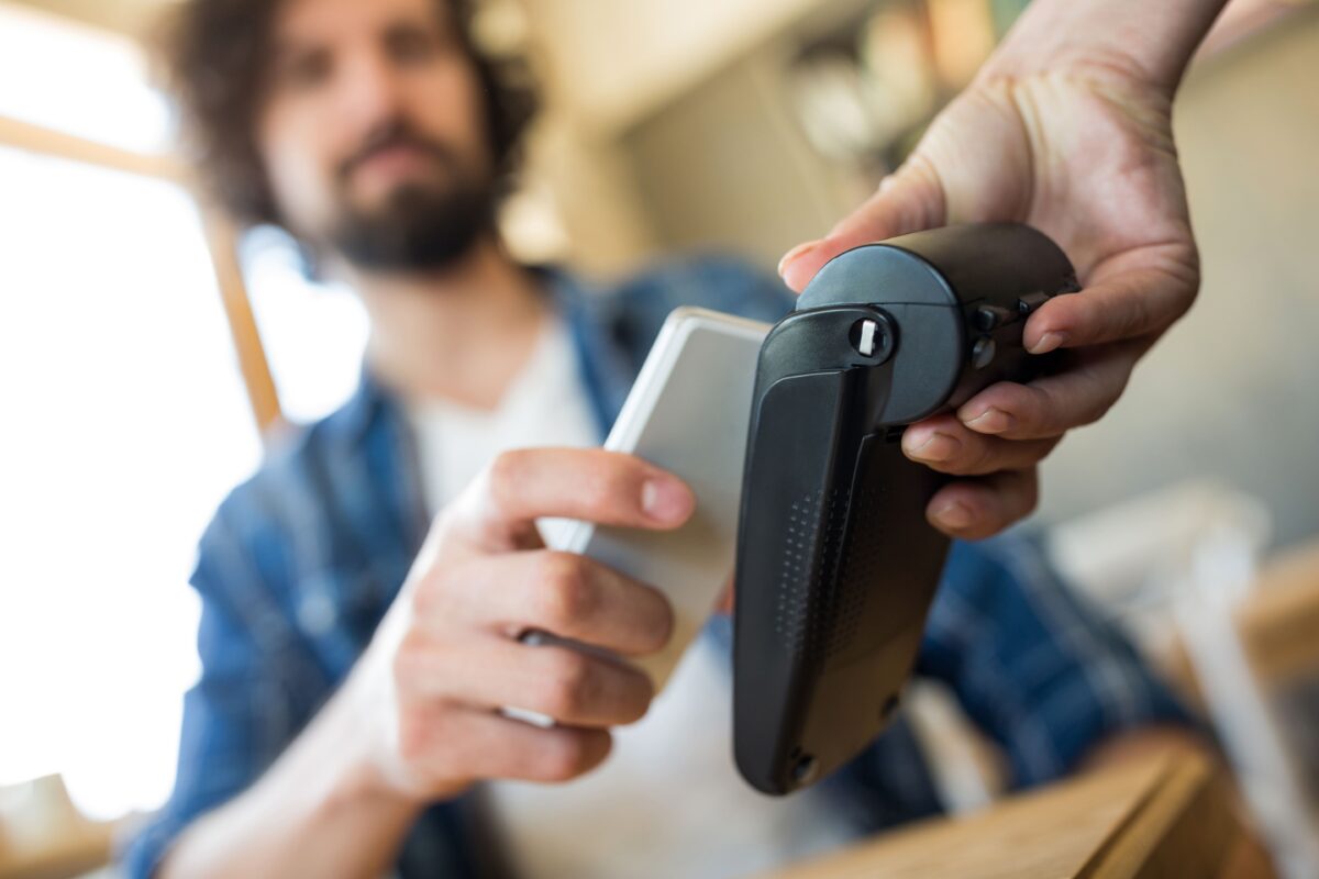 man-paying-with-nfc-technology-on-mobile-phone-min